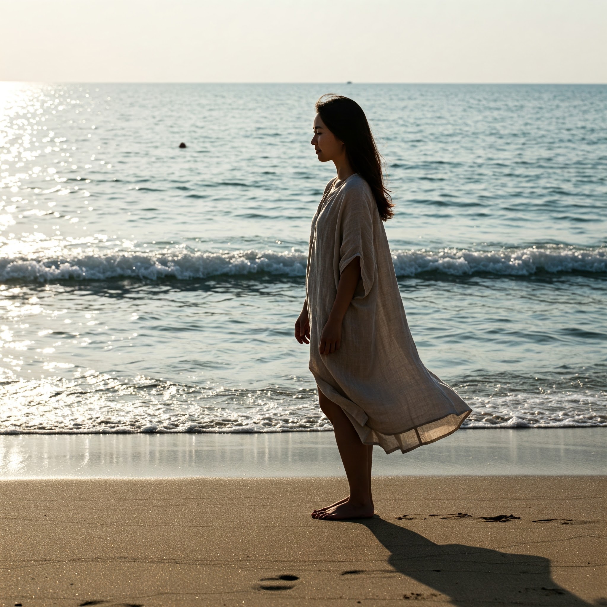 Barefoot silhouette on a beach with a large ocean backdrop, symbolizing grounding and ocean wellness.